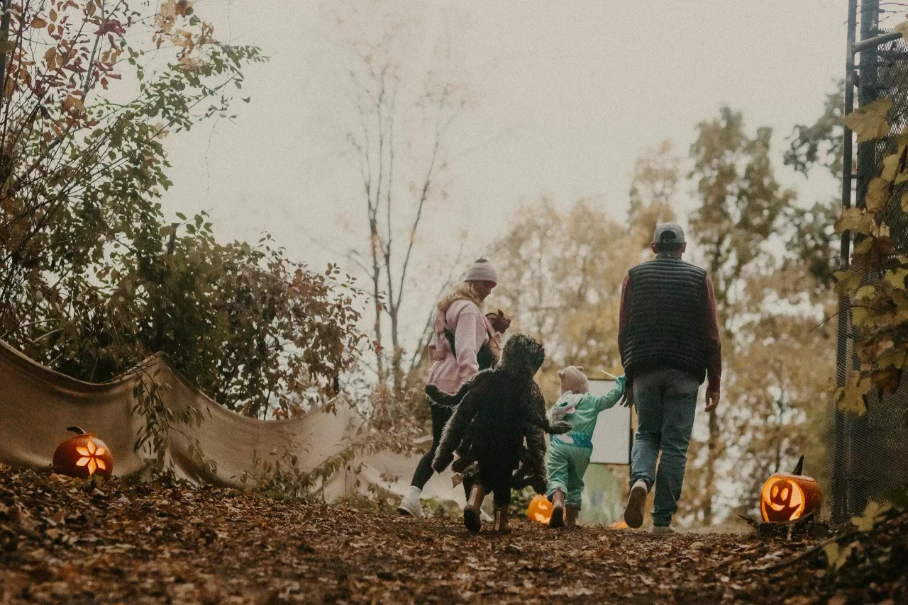 A family beside jack-o-lanterns at the RBG Pumpkin Trail